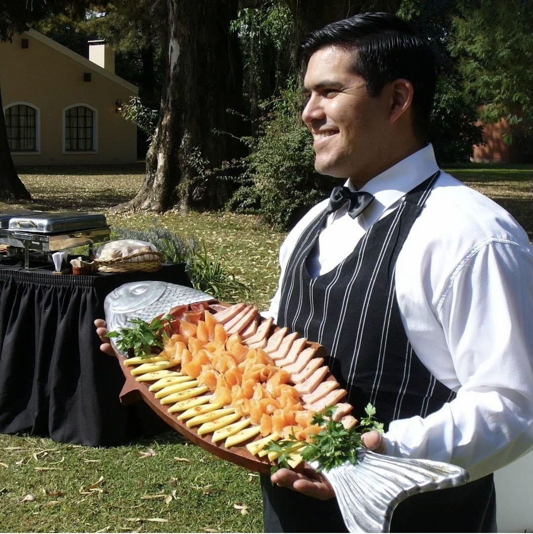 Mozo sirviendo bandeja de salmón ahumado en un evento al aire libre